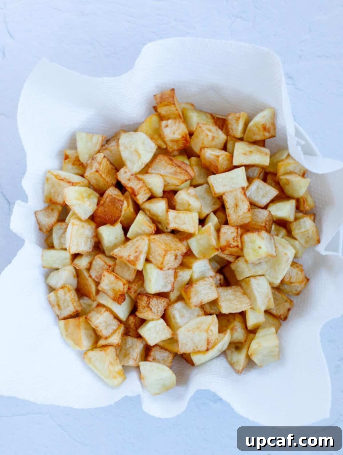 Cubed potatoes frying in a deep pan until golden and crispy.