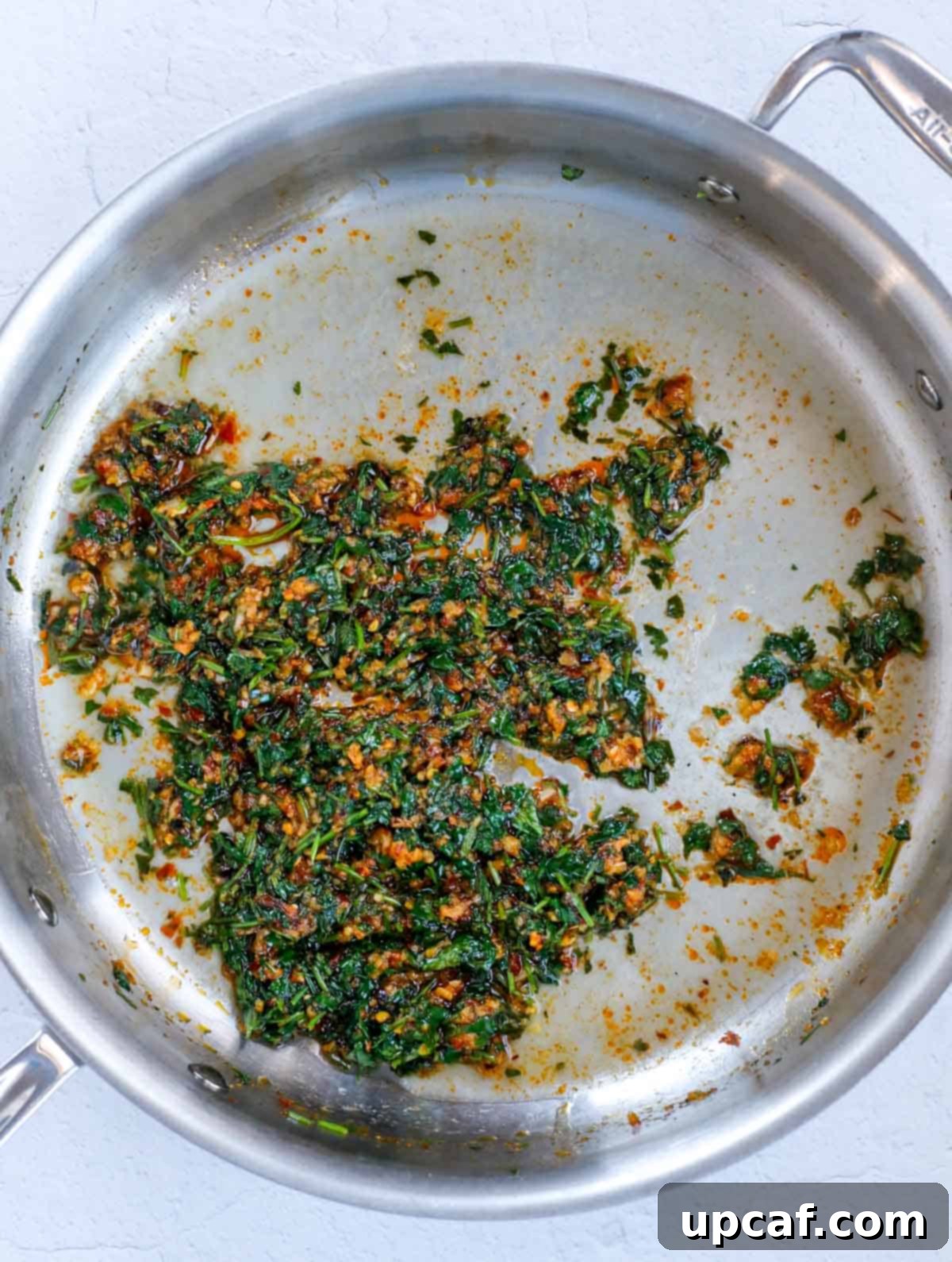 Crispy Batata Harra potatoes being tossed with the spicy garlic and cilantro sauce in a pan.