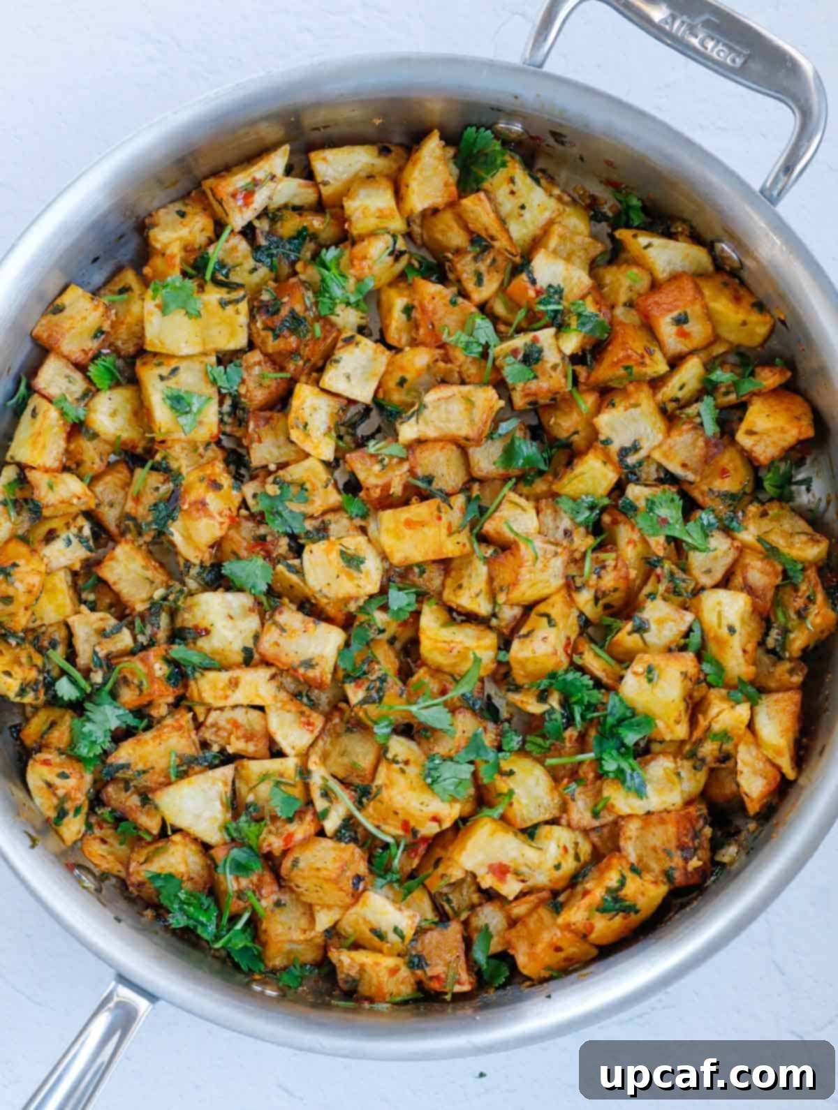 Finished Batata Harra dish in a stainless steel pan, garnished and ready to serve.