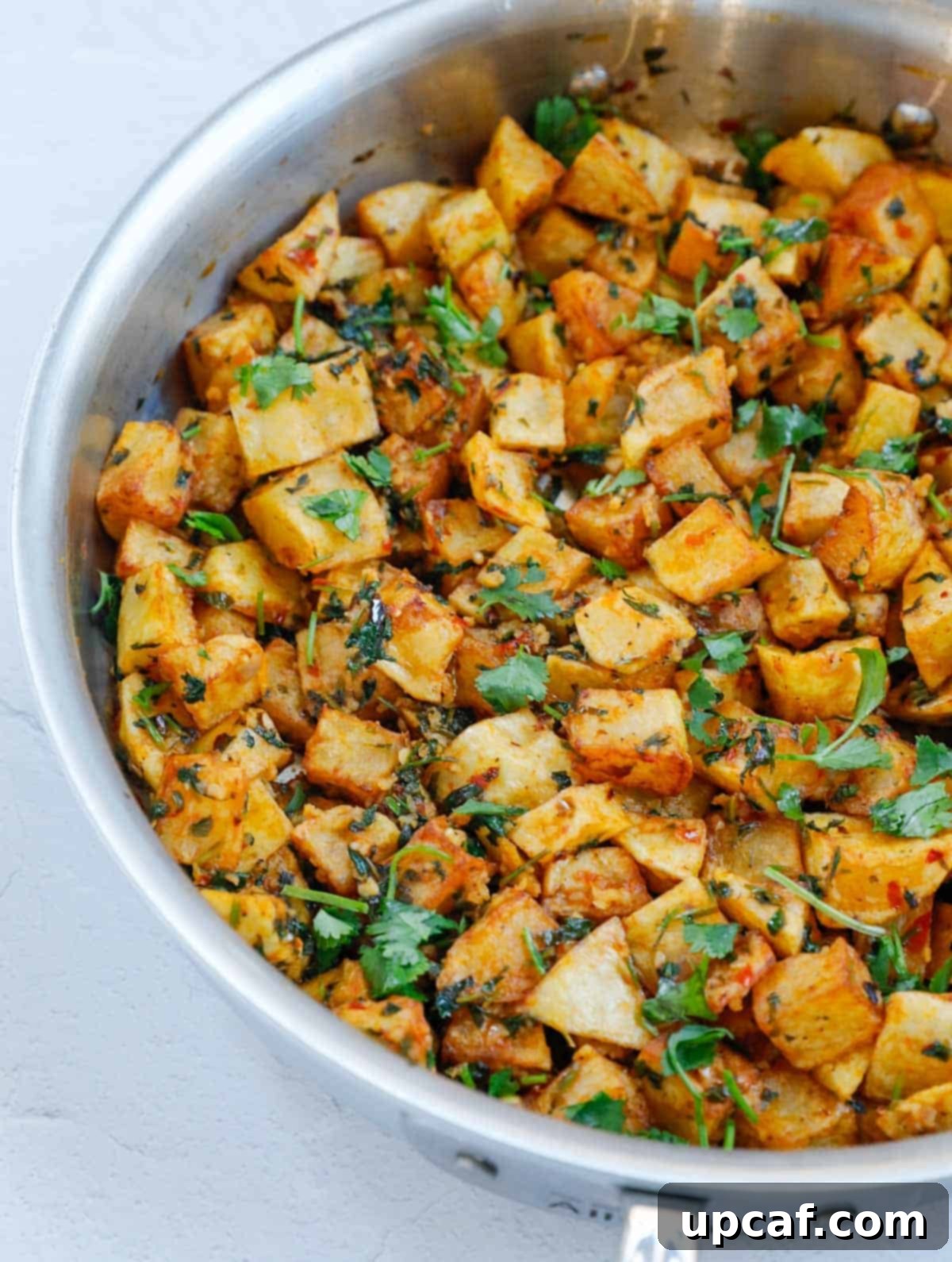A fresh batch of Batata Harra, perfectly spiced and garnished, presented beautifully in a pan.
