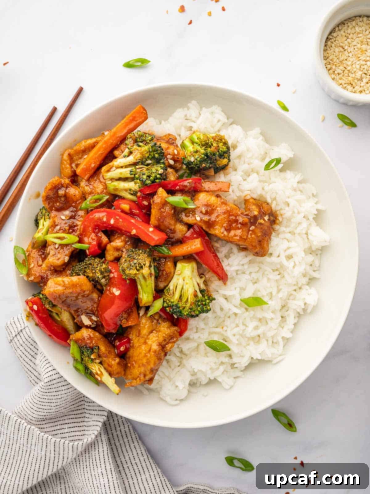 Chinese hunan chicken served over rice with chopsticks.
