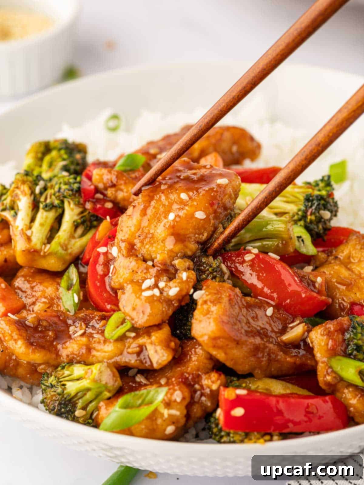 Chopsticks pick up a piece of hunan style chicken.