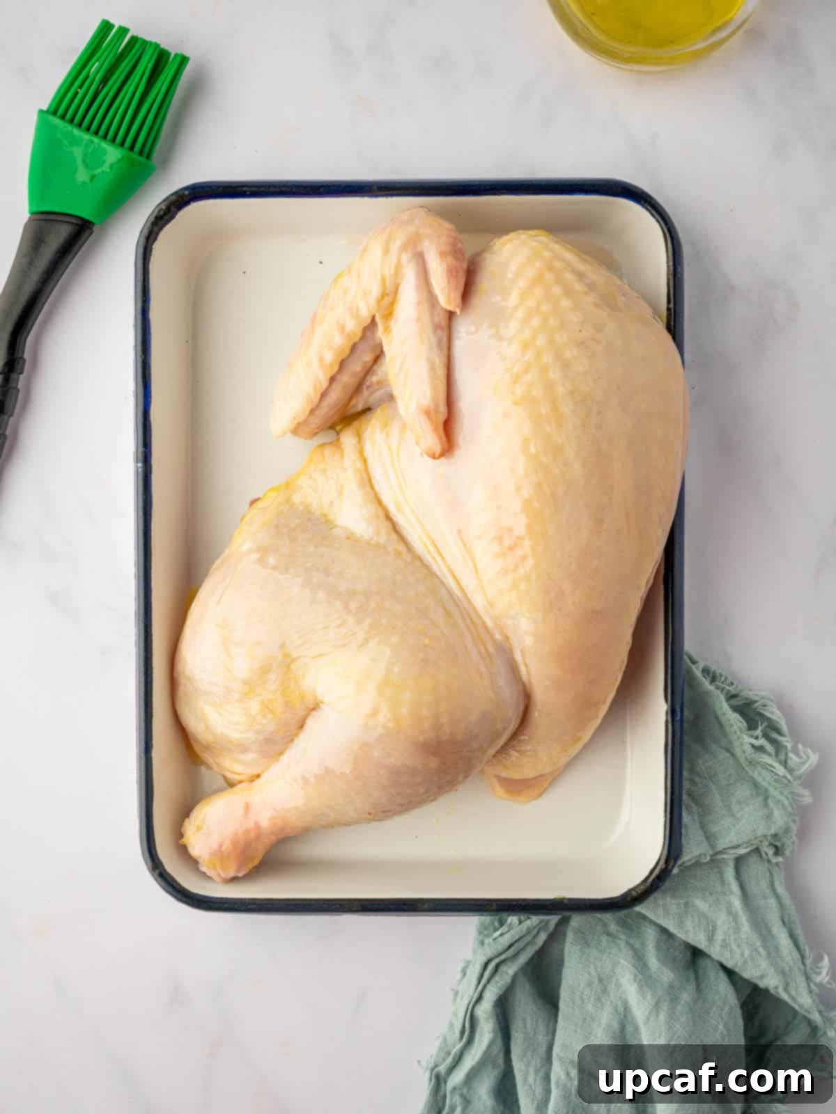 A raw half chicken, carefully prepped and ready for seasoning before grilling.