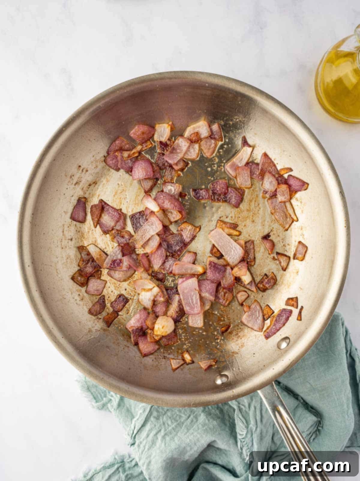 Close-up view of sautéed onions in a skillet, turning translucent and slightly golden, forming the base of the Pasanda gravy.