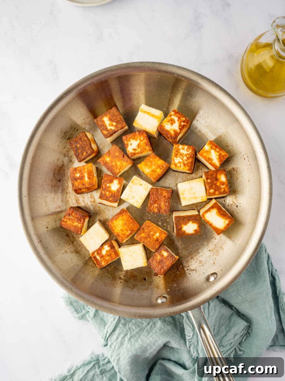 Paneer cubes being pan-fried in a hot skillet, achieving a beautiful golden-brown color on all sides.