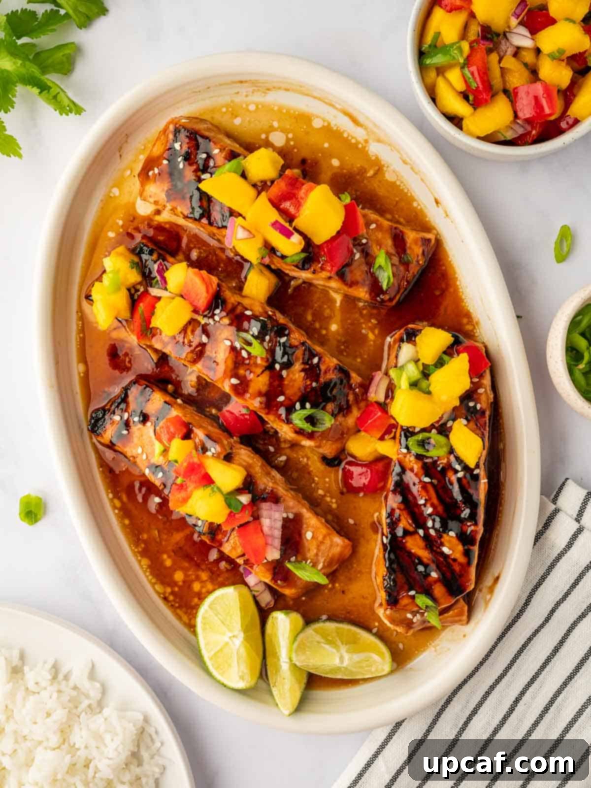 Sweet and Savory Teriyaki Salmon 2 Perfectly grilled salmon fillet topped with a colorful mango salsa, served on a white plate, ready to be enjoyed.