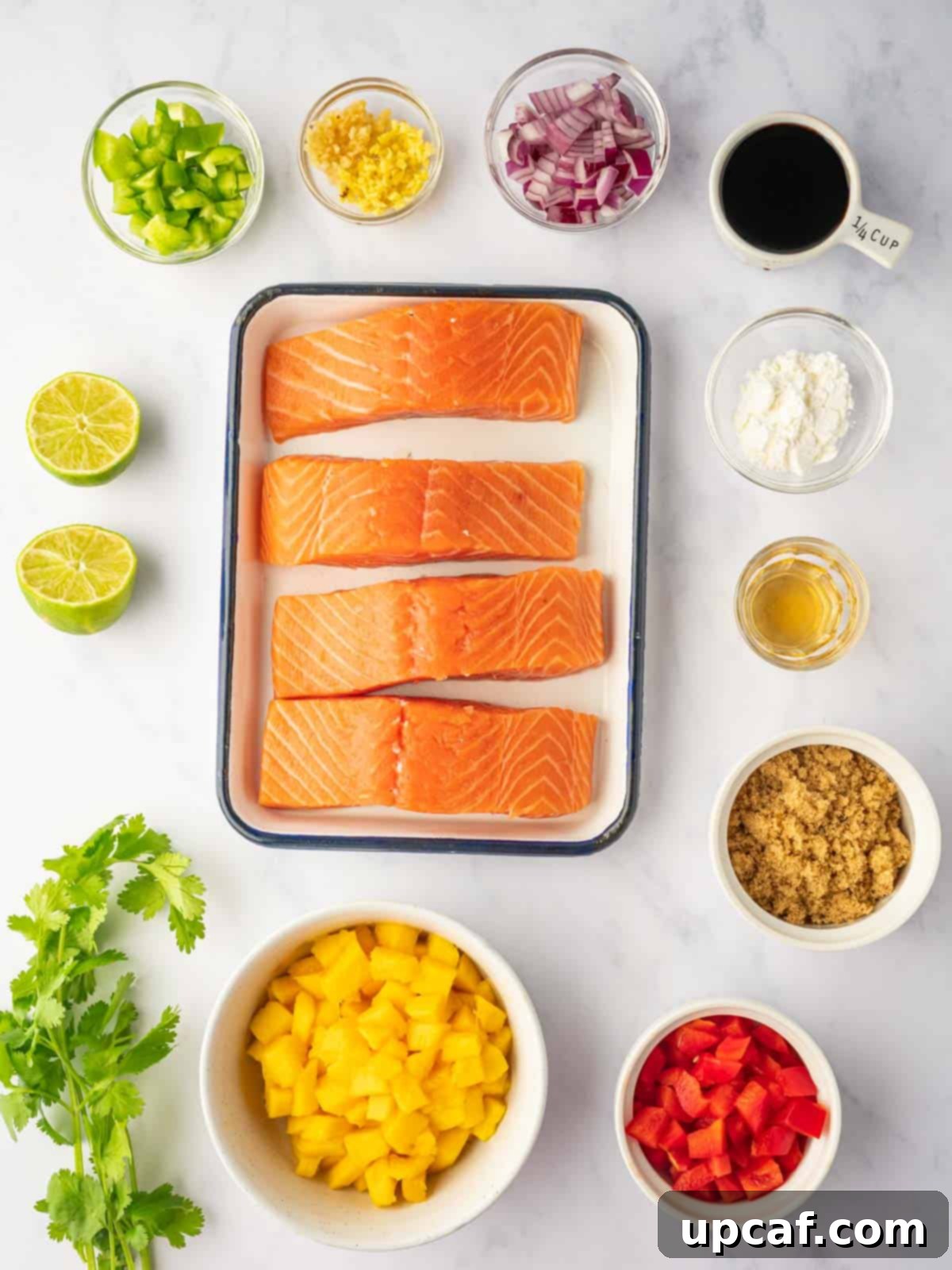 Sweet and Savory Teriyaki Salmon 3 Various fresh ingredients laid out on a kitchen counter, including salmon fillets, ingredients for teriyaki sauce, and fresh produce for mango salsa.