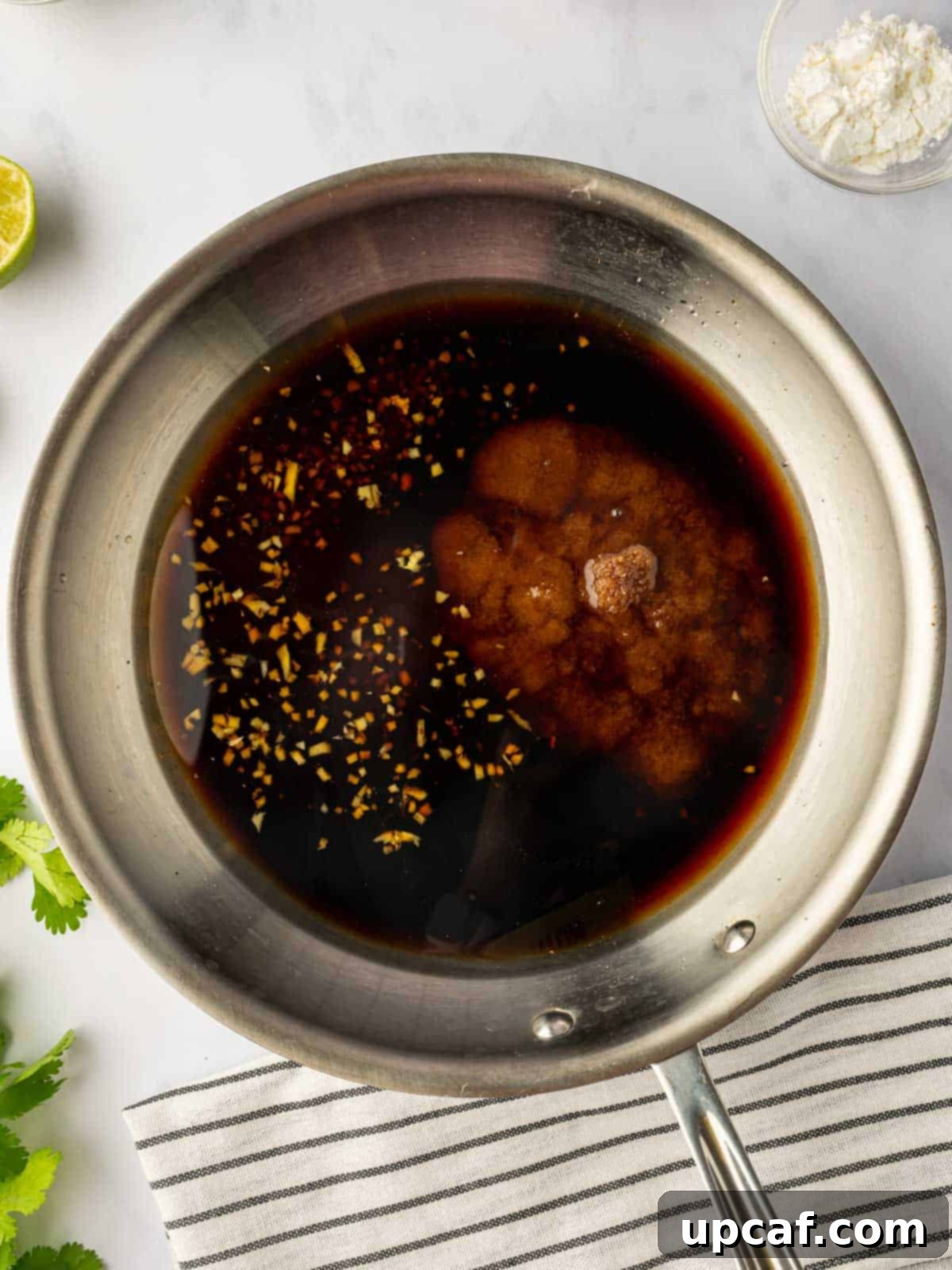 Sweet and Savory Teriyaki Salmon 4 A saucepan on a stovetop with teriyaki marinade simmering, showing the rich, dark liquid bubbling gently.