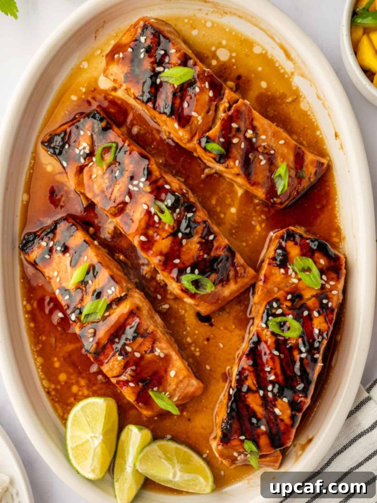 Sweet and Savory Teriyaki Salmon 7 Close-up of grilled teriyaki salmon fillets garnished with green onions and sesame seeds, highlighting the glossy glaze.
