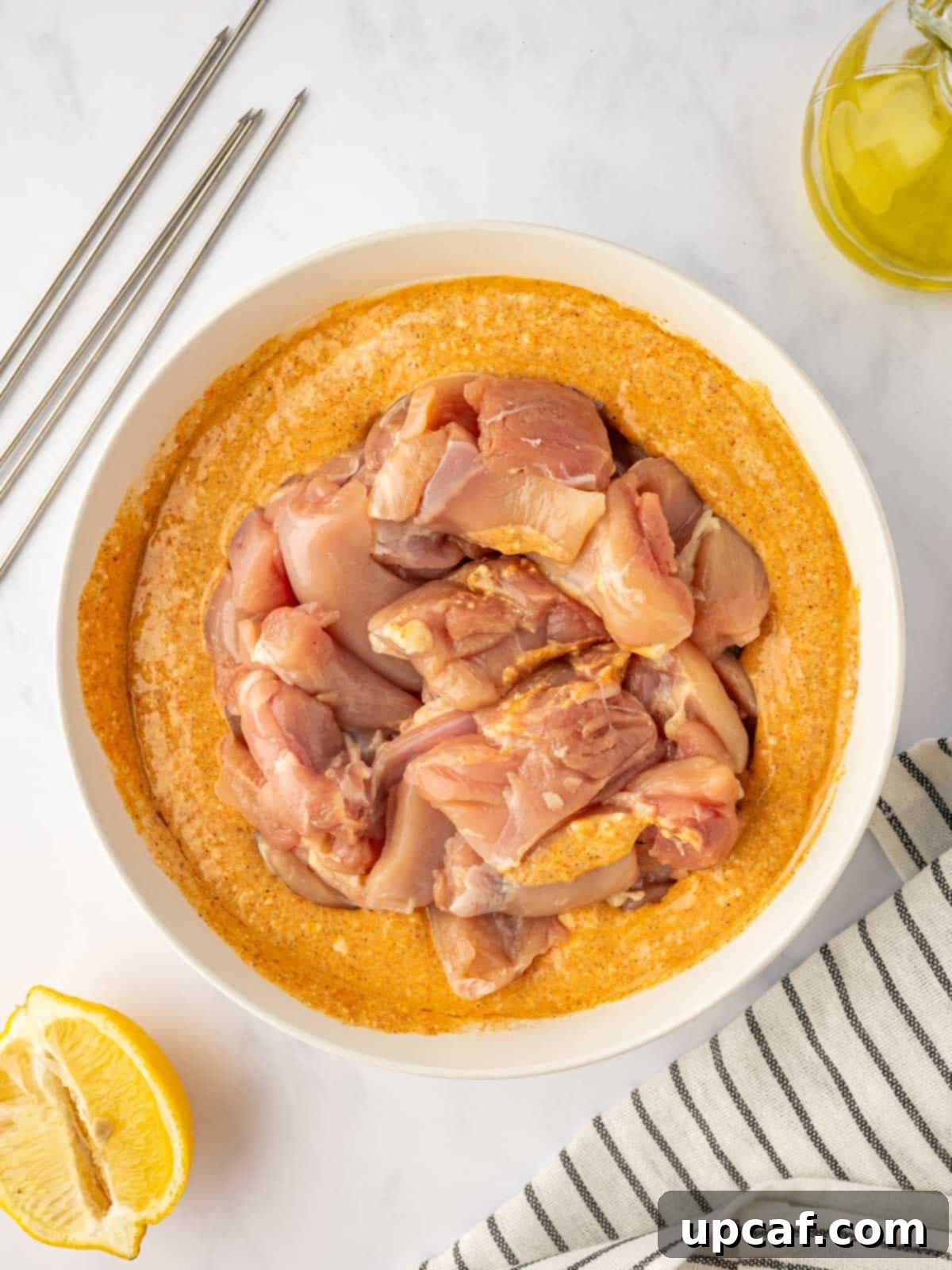 Raw chicken pieces are carefully coated and marinating in the rich, reddish Tandoori yogurt sauce.