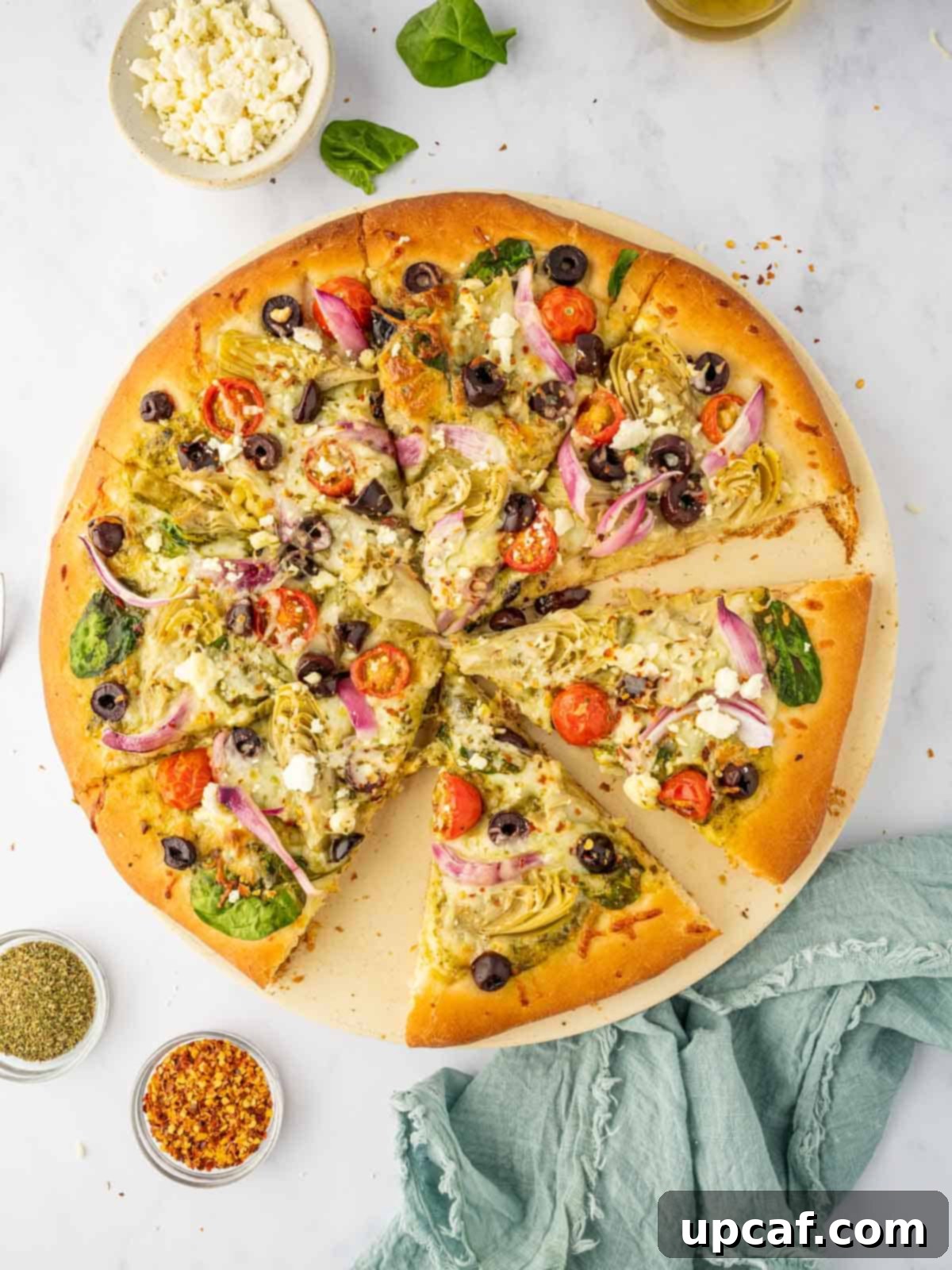 Sliced of homemade Mediterranean pizza on a pizza stone.