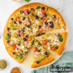 Sliced of homemade mediterranean pizza on a pizza stone.