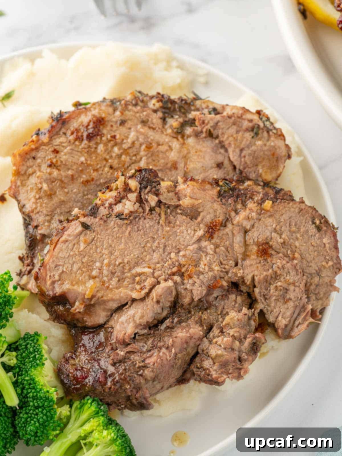 Rosemary Garlic Boneless Lamb Roast 7 Leg of lamb slices on a plate.