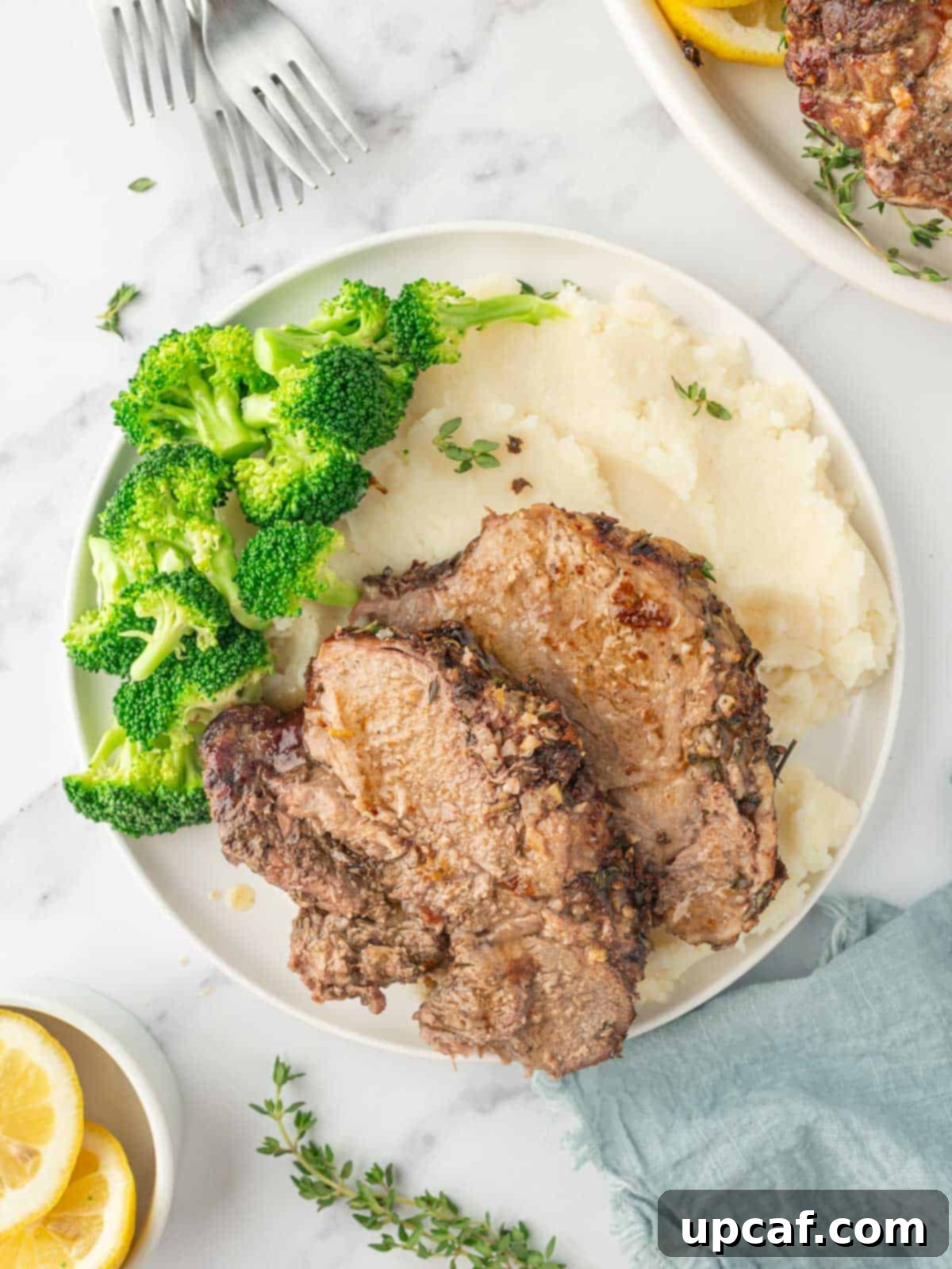 Rosemary Garlic Boneless Lamb Roast 8 Sliced of roasted lamb on a plate with mashed potatoes and broccoli.