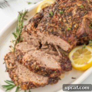Rosemary Garlic Boneless Lamb Roast 9 Leg of lamb with slices cut garnished with lemon and rosemary.