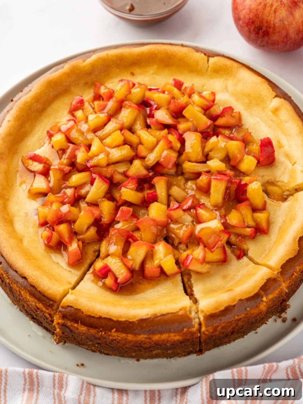 A whole Cinnamon Apple Cheesecake, beautifully topped with a generous layer of spiced apples, ready to be sliced and served.