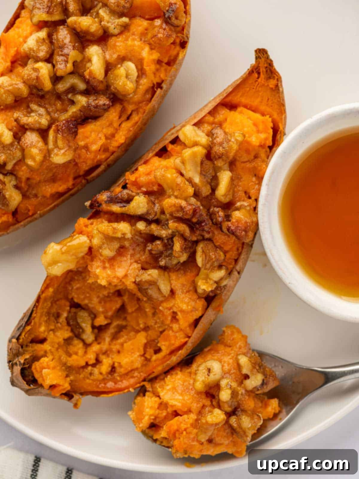 Maple Glazed Sweet Potatoes with Toasted Walnuts 11 A spoon scooping a bite of sweet potatoes, showing the creamy filling and walnut topping.