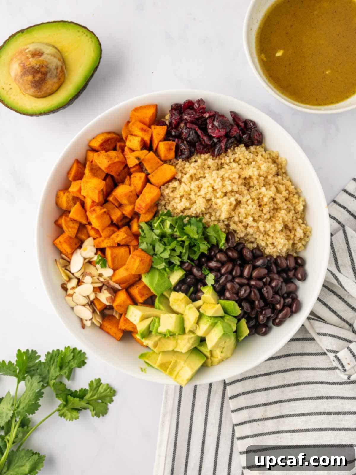 Roasted Sweet Potato Quinoa Salad 7 Various ingredients for quinoa salad piled in a large bowl, including roasted sweet potatoes, quinoa, black beans, avocado, cranberries, and almonds.