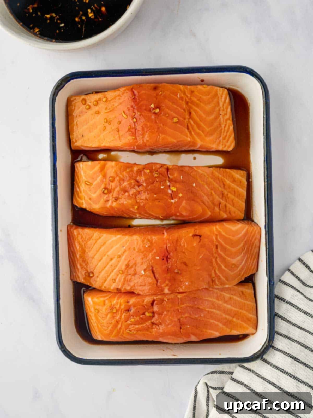 Salmon is marinated in a dish with teriyaki sauce.