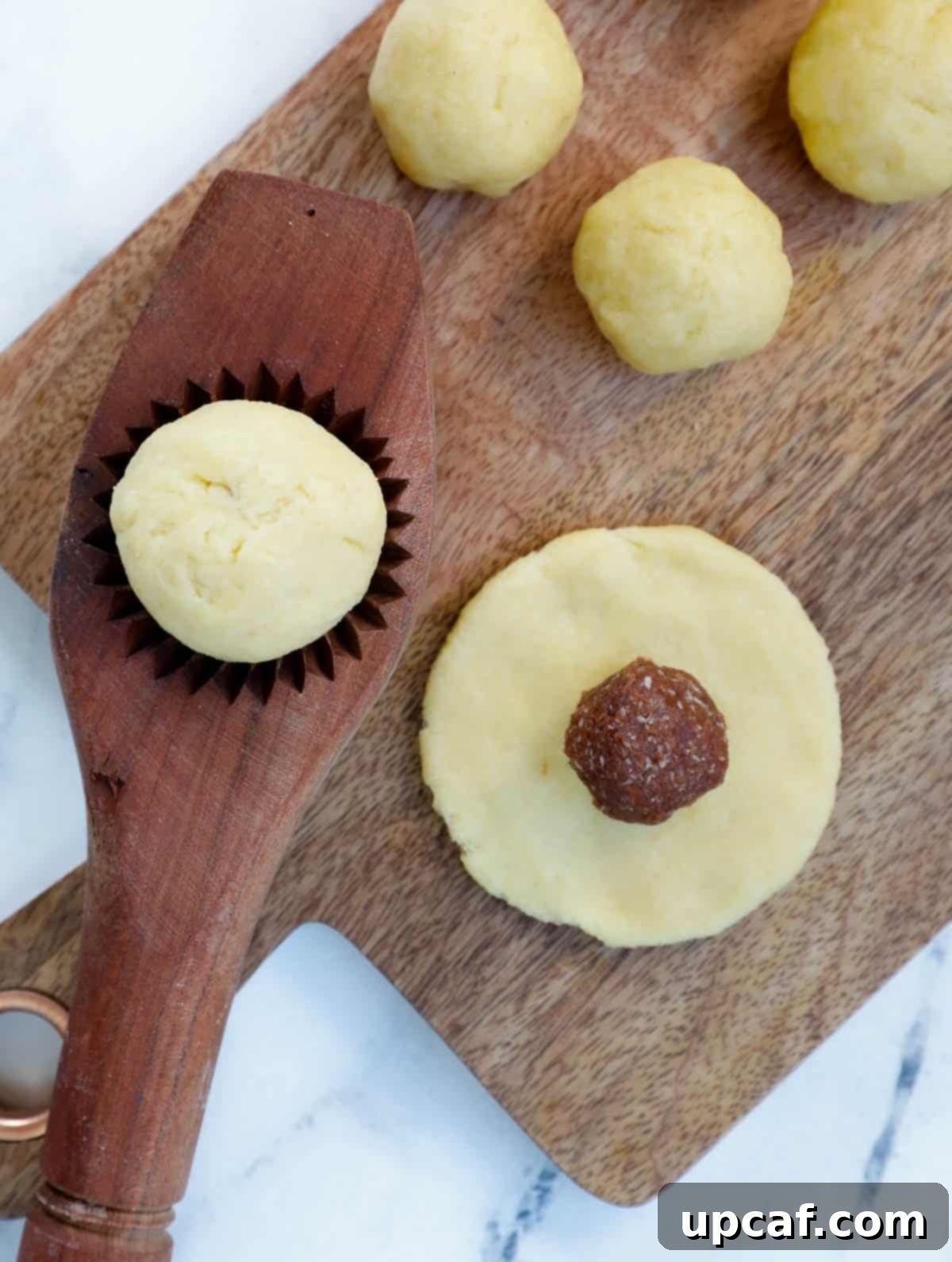 Display of a mamaoul dough flattened out with a piece of date ball on top and the ball shown in a maamoul mold.