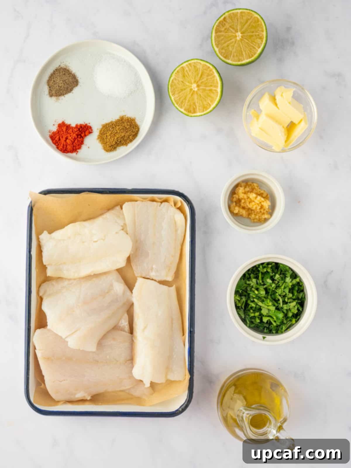 A vibrant selection of ingredients laid out, including cod fillets, fresh cilantro, limes, butter, garlic, and spices, ready for making herb lime baked cod.