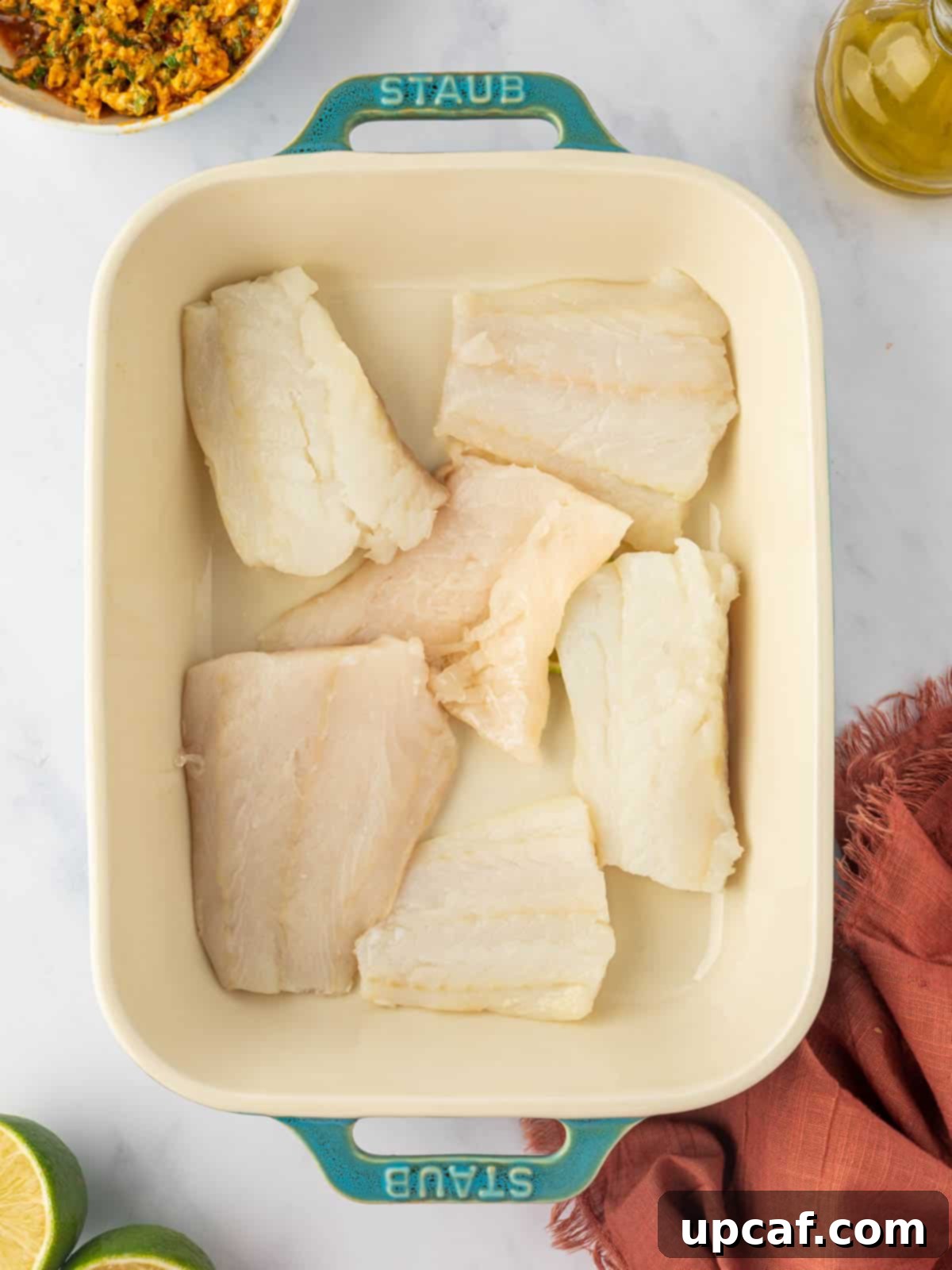 Dry cod fillets neatly arranged in a baking dish, ready for seasoning.