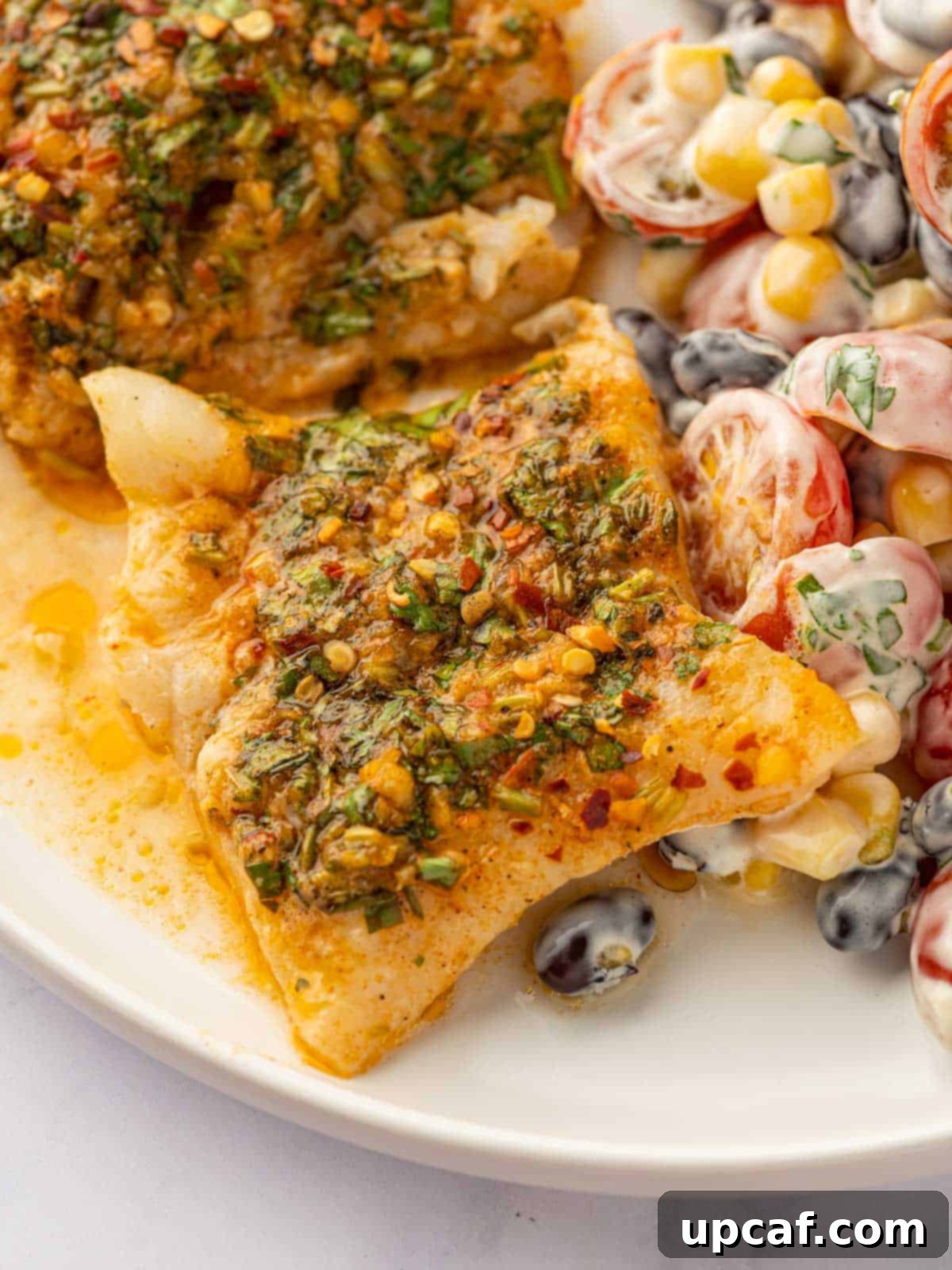 A simple cod recipe served on a white plate with a fresh tomato salad, showcasing a perfect weeknight meal.