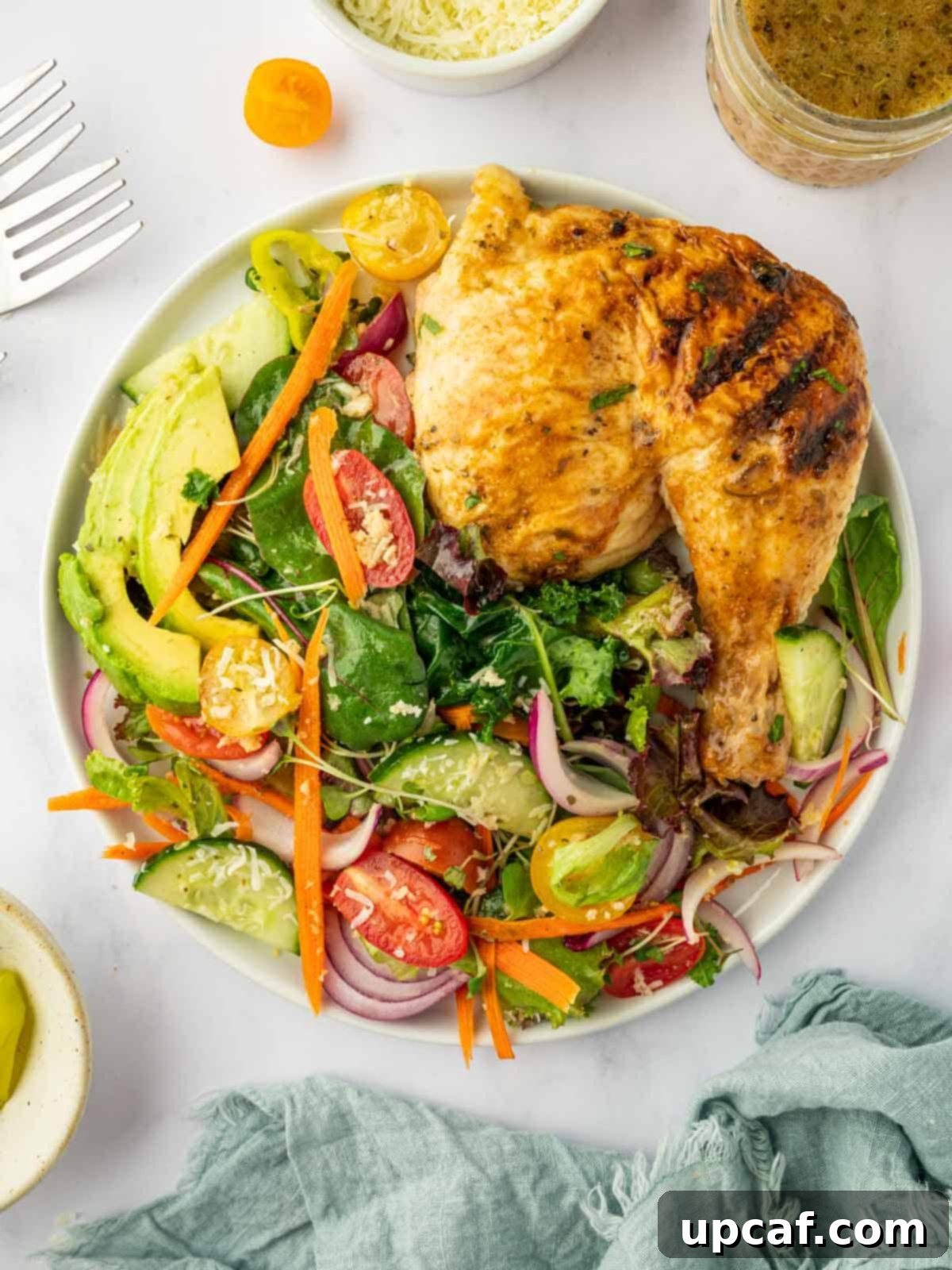 A vibrant traditional house salad served alongside grilled chicken on a white plate, showcasing a complete and healthy meal.