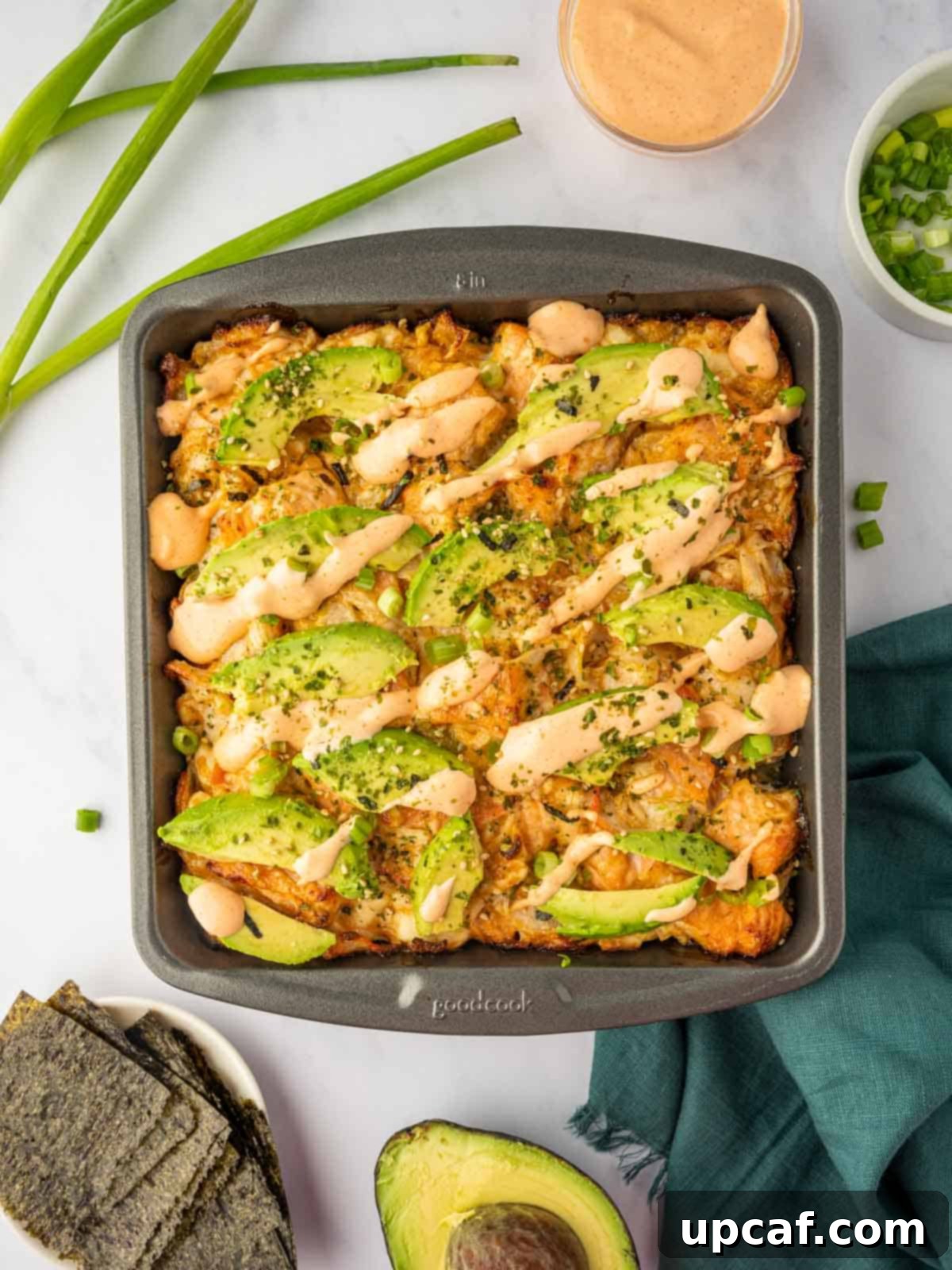 A golden-brown baked salmon sushi casserole in a square pan, ready to be served.