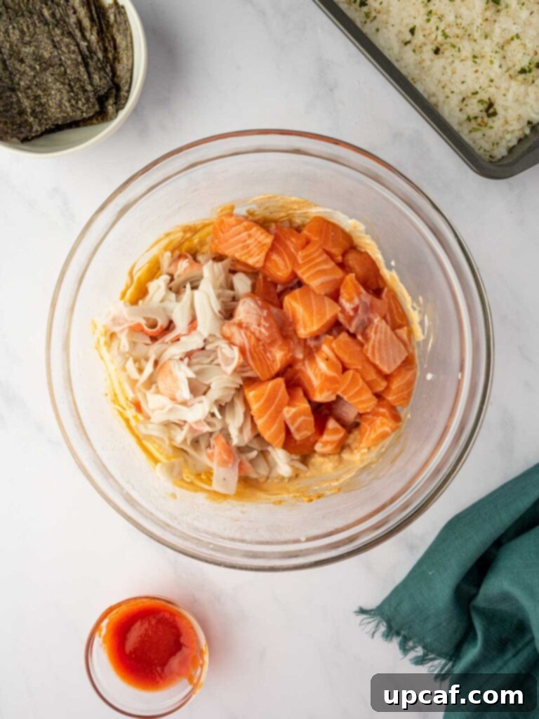 A bowl filled with the prepared salmon, imitation crab, and creamy mixture, ready for layering.