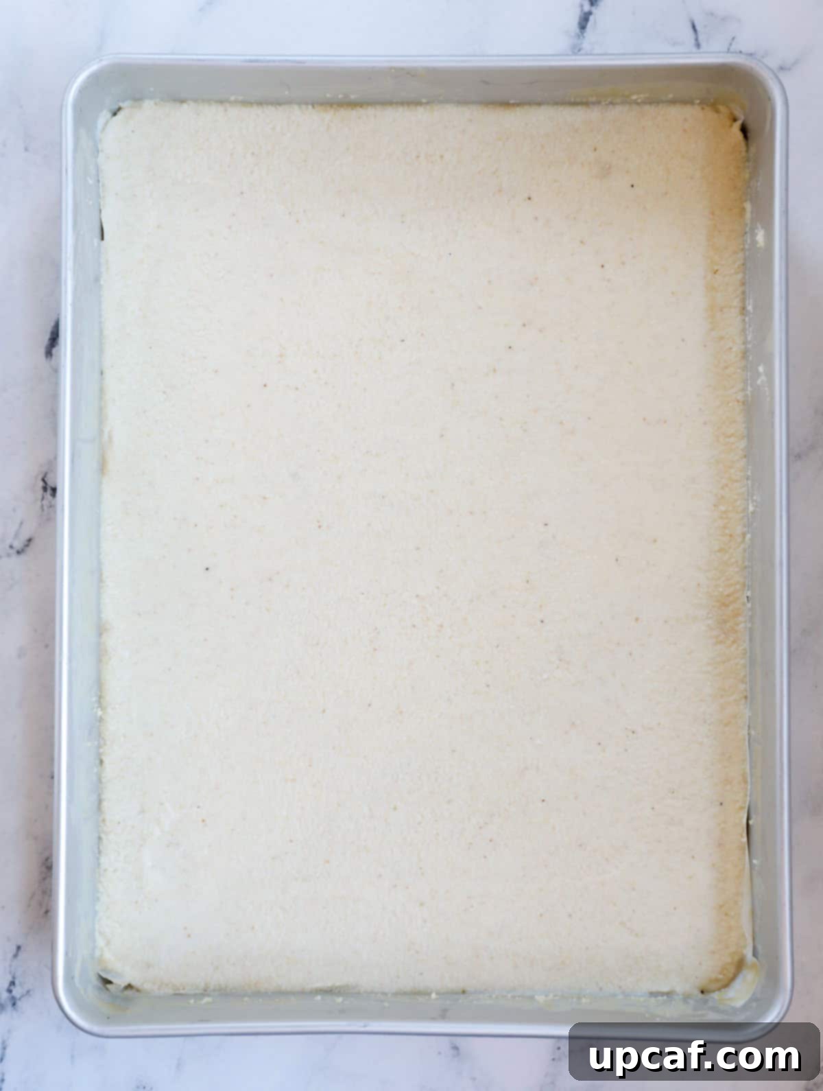 Namoura batter evenly spread in a baking pan, ready for the next steps.