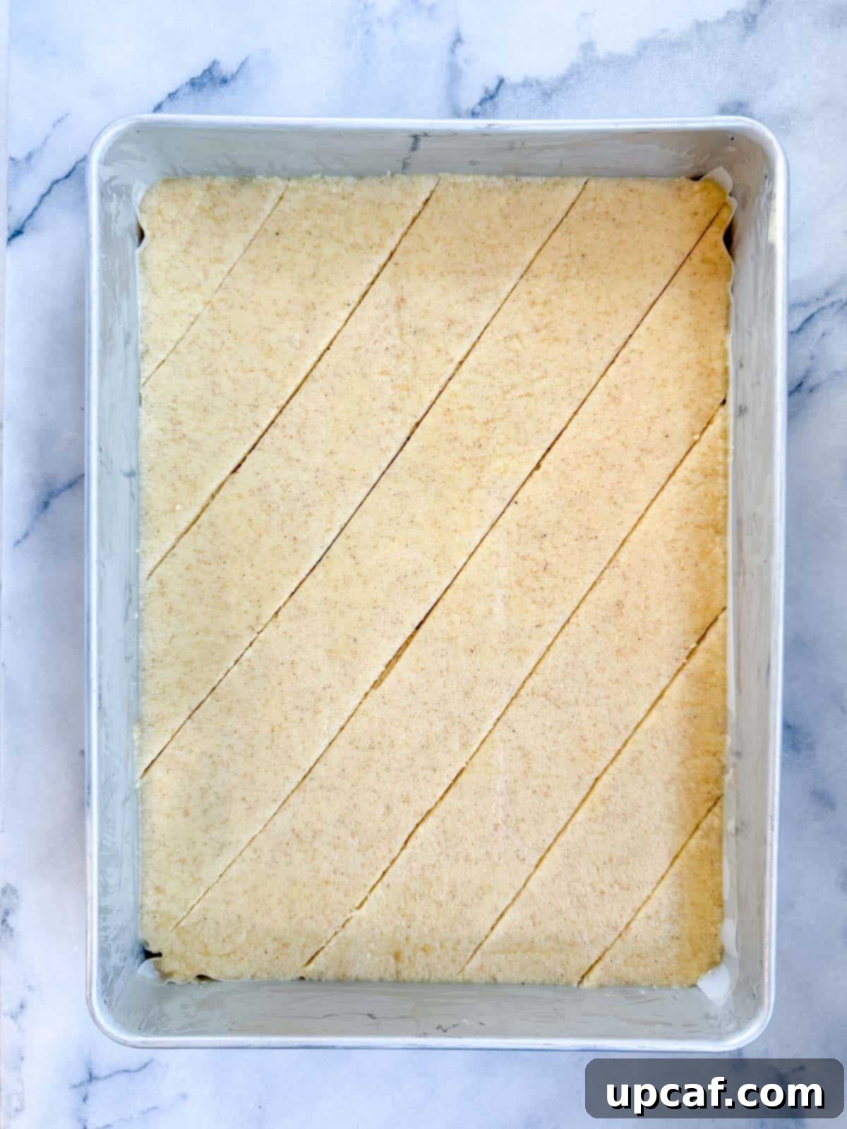 Namoura batter in the pan, with lines scored into the surface using a knife, creating a grid for portioning.