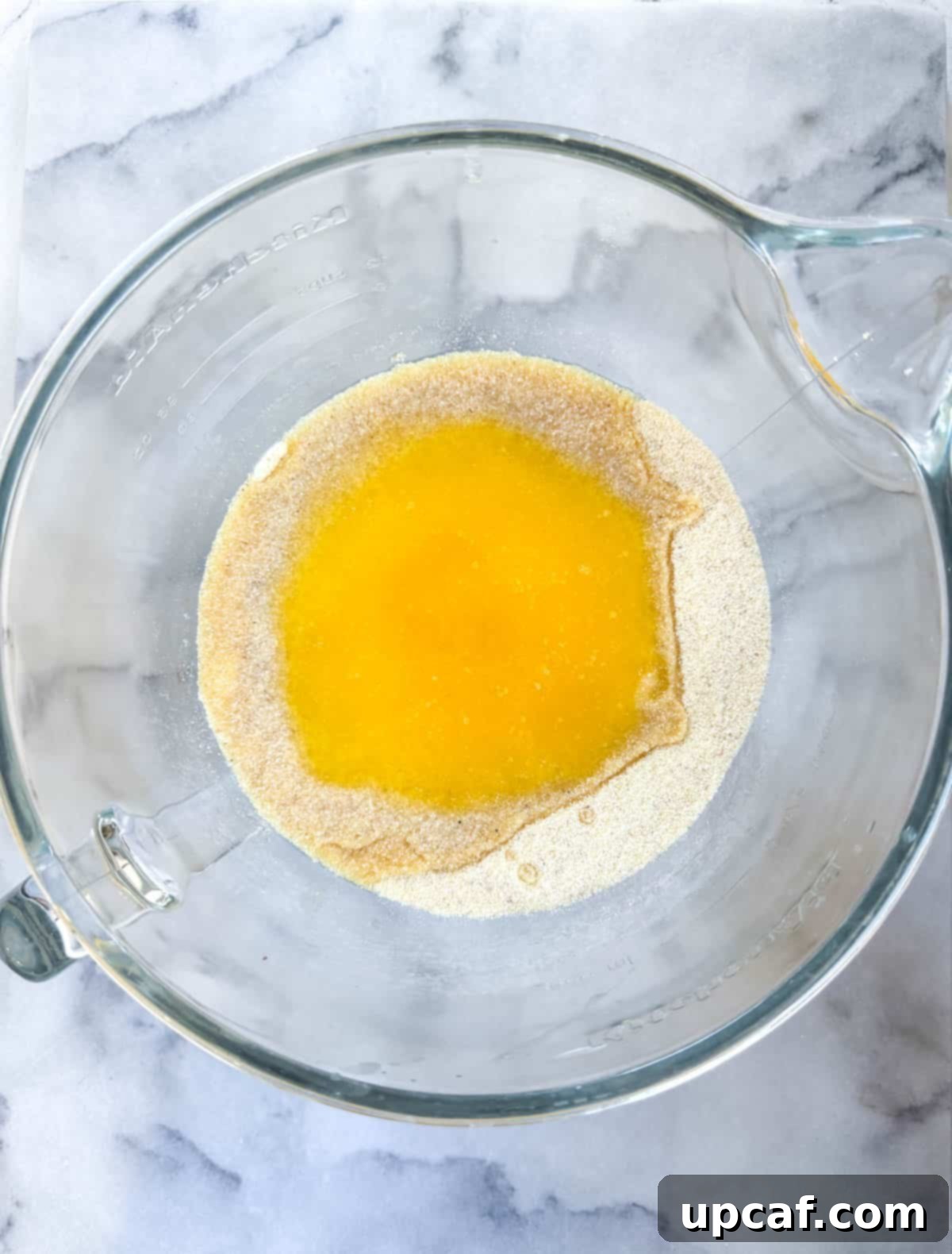 Coarse and fine semolina grains in a bowl, with warm melted butter being poured over them.