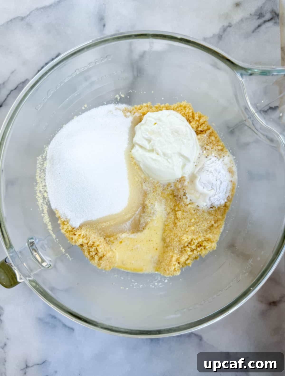 All the wet and dry ingredients for Namoura batter, including semolina, yogurt, milk, and baking powder, gathered in a bowl before mixing.