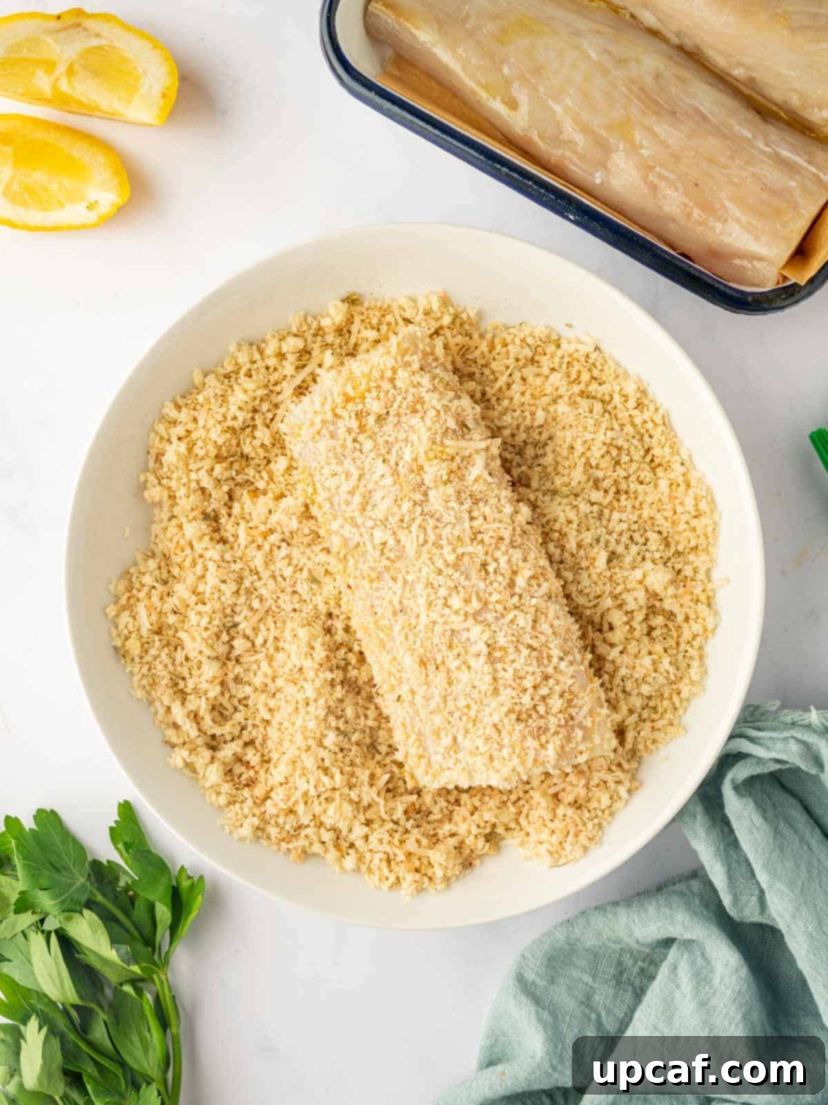 A skilled hand carefully coating a mahi mahi fish fillet with panko crumbs, ensuring an even and thorough breading before cooking.