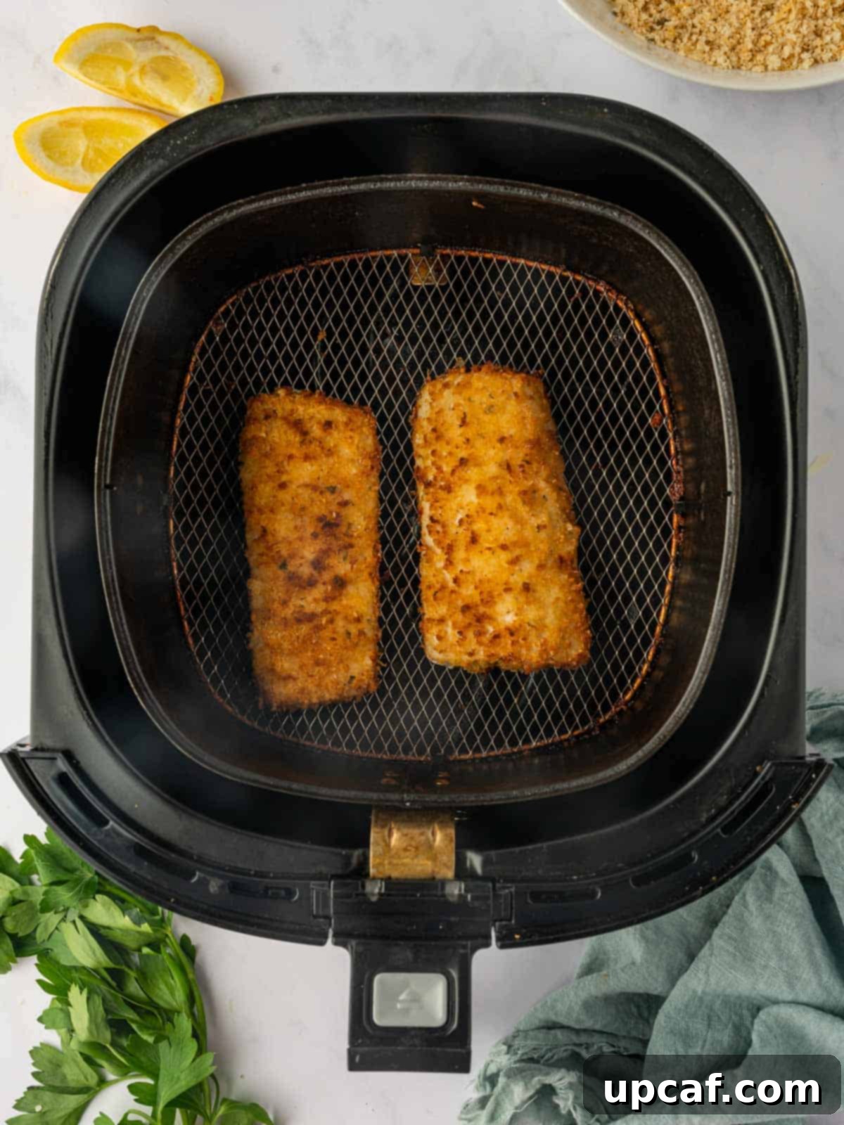 Perfectly cooked, golden-brown breaded Mahi Mahi fish fillets resting in the air fryer basket, showcasing their crispy texture after air frying.