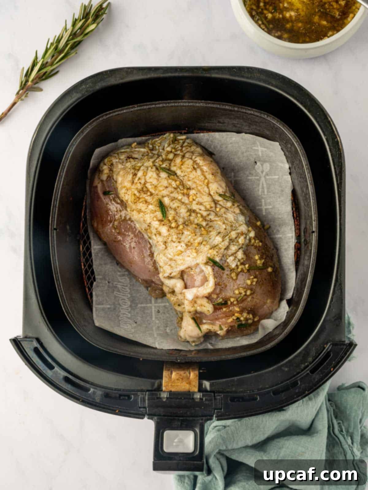 Seasoned turkey breast placed in an air fryer basket, ready to be cooked.