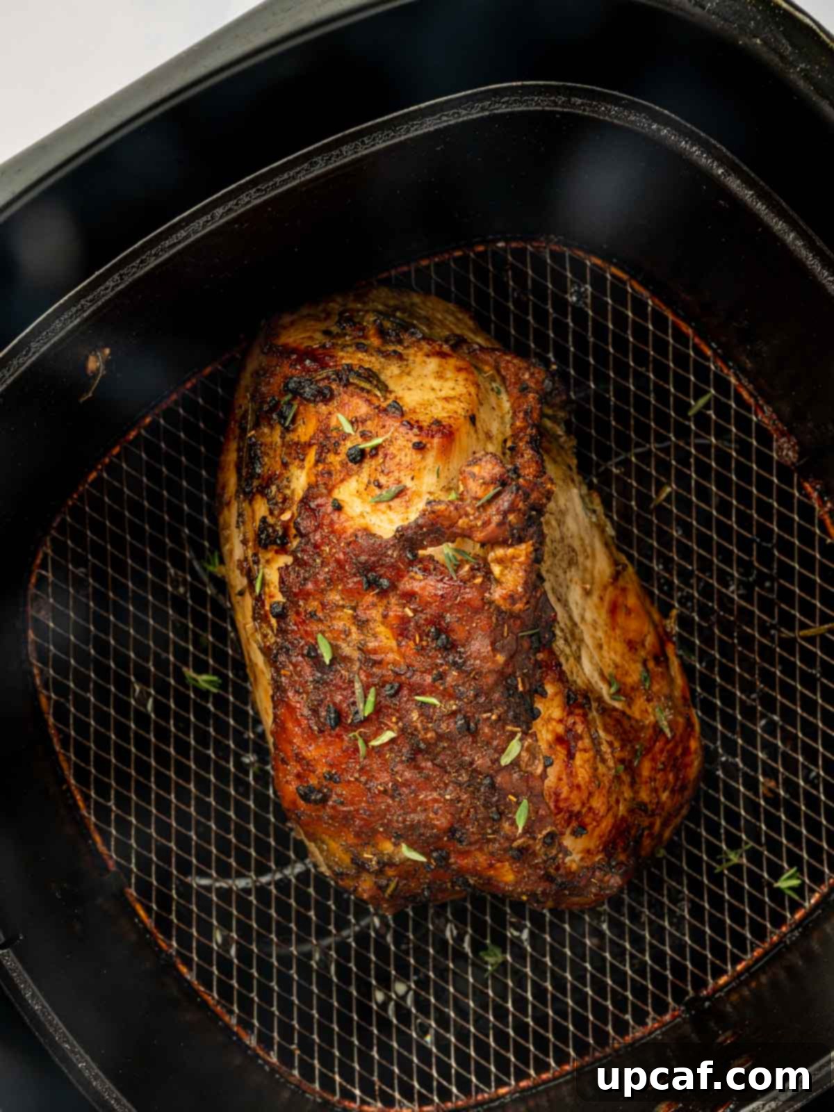 Whole turkey breast cooking in an air fryer, with a golden-brown finish.