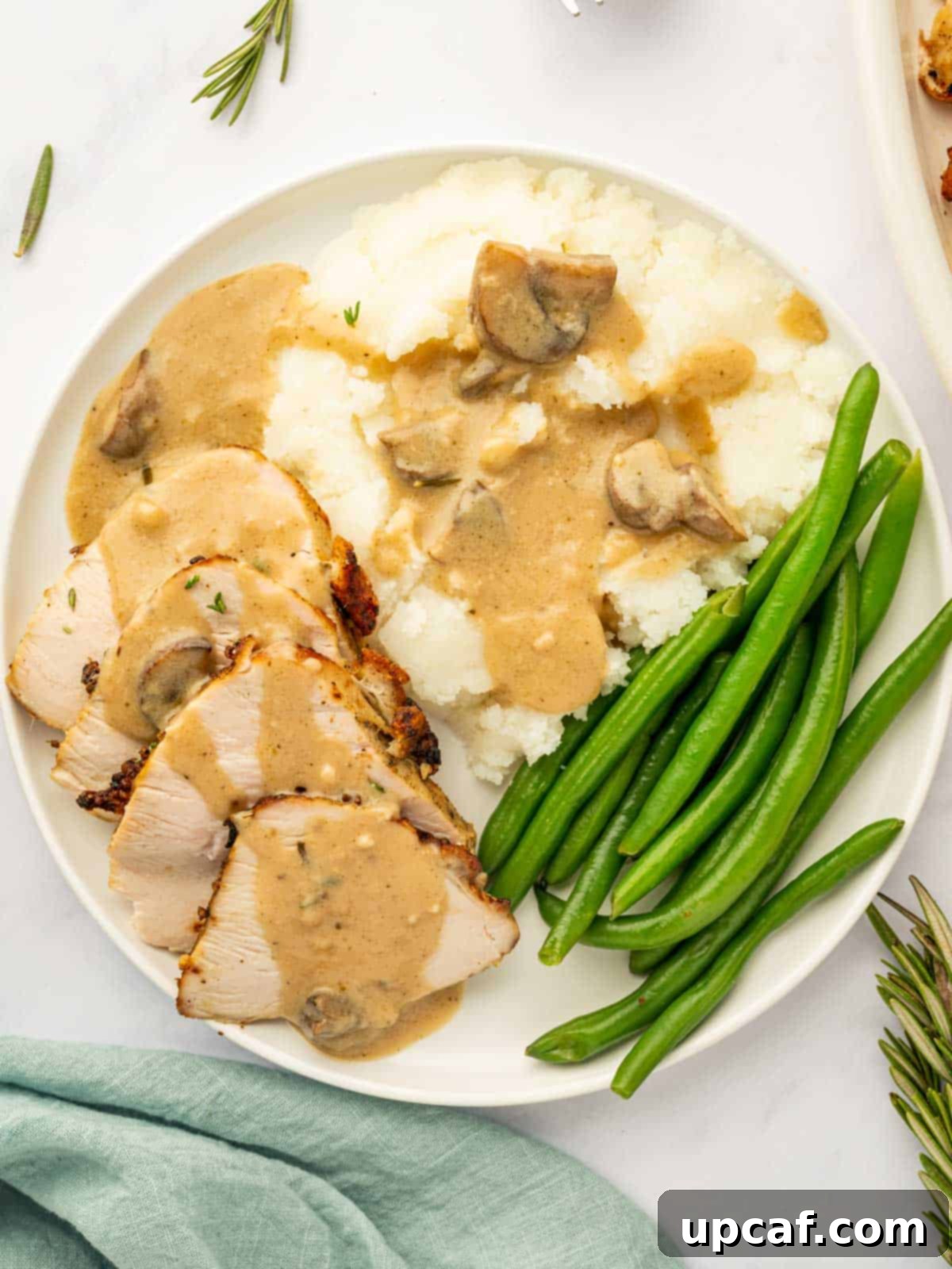 A festive platter with sliced turkey, gravy, mashed potatoes, and green beans.