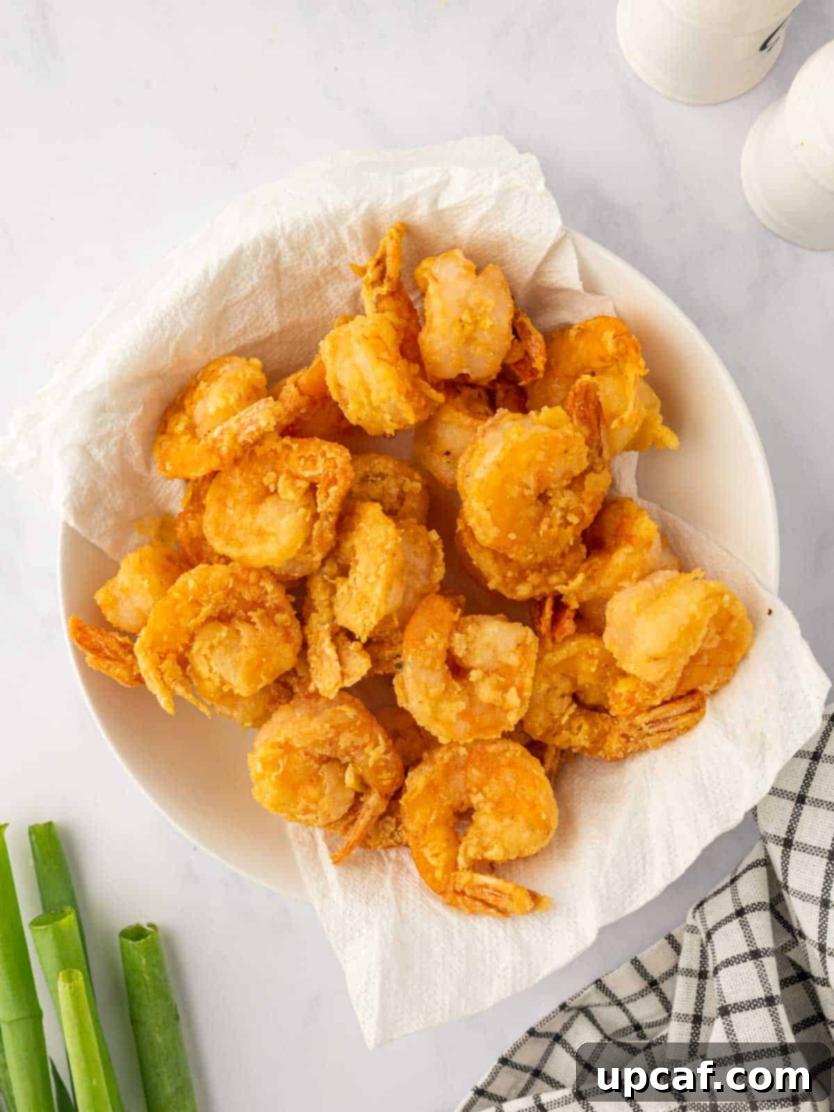 Golden-brown, crispy fried shrimp draining on paper towels, waiting to be tossed with aromatics.