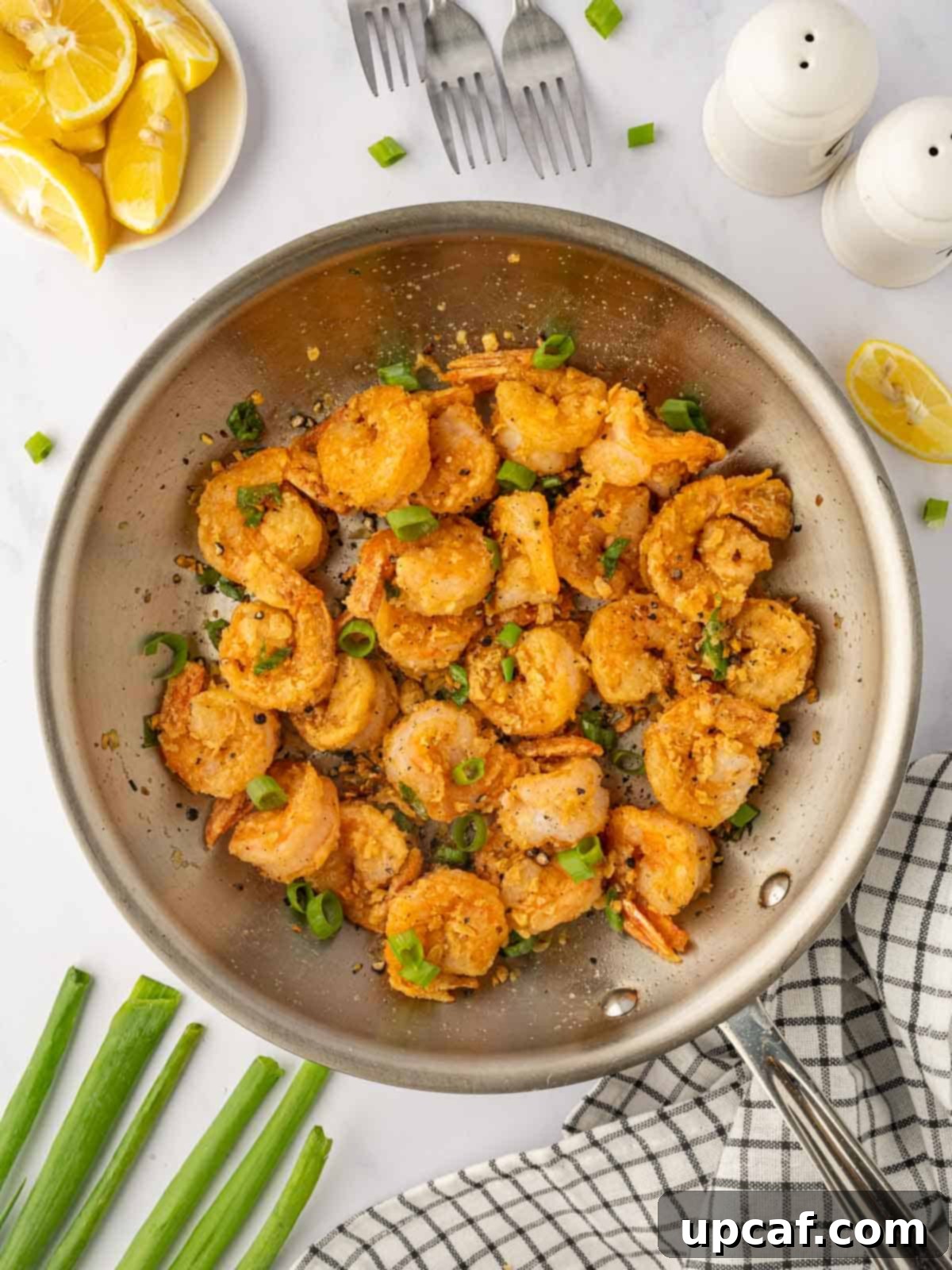 A close-up of Chinese salt and pepper shrimp tossed with aromatics in a skillet, showcasing its vibrant colors and crispy texture.