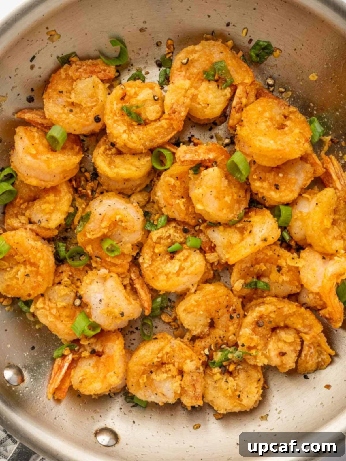 A close-up shot of crispy Chinese salt and pepper shrimp, showcasing its perfectly seasoned golden coating and succulent texture.