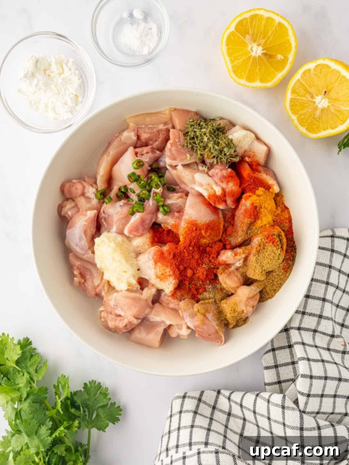 Golden Crispy Chicken Pakora 4 Raw chicken pieces are seasoned with a vibrant array of Indian spices in a bowl.