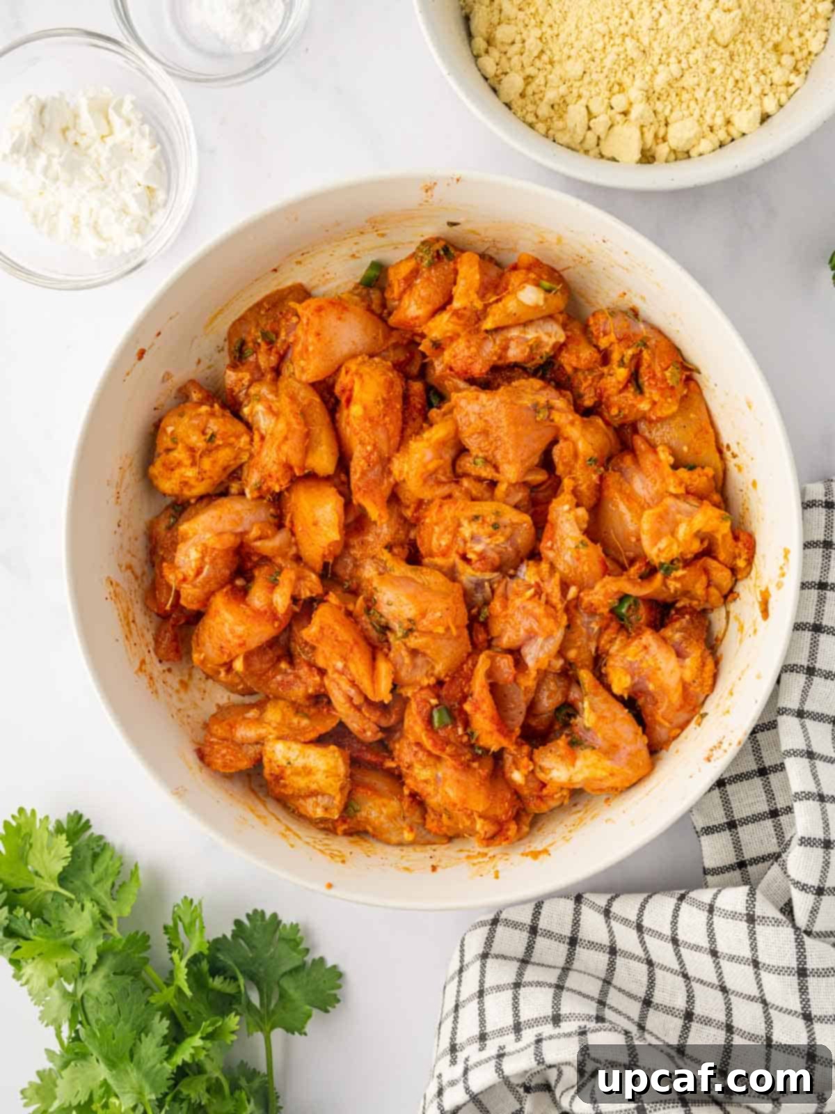 Golden Crispy Chicken Pakora 5 Close-up of chicken cubes thoroughly mixed with a rich, spicy marinade in a bowl, ready for soaking.