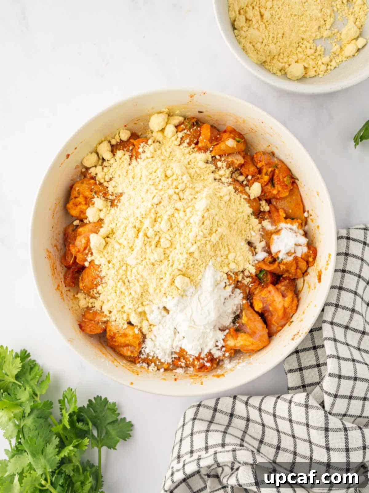 Golden Crispy Chicken Pakora 6 Marinated chicken pieces are being tossed with gram flour and cornstarch in a large mixing bowl to form the pakora batter.