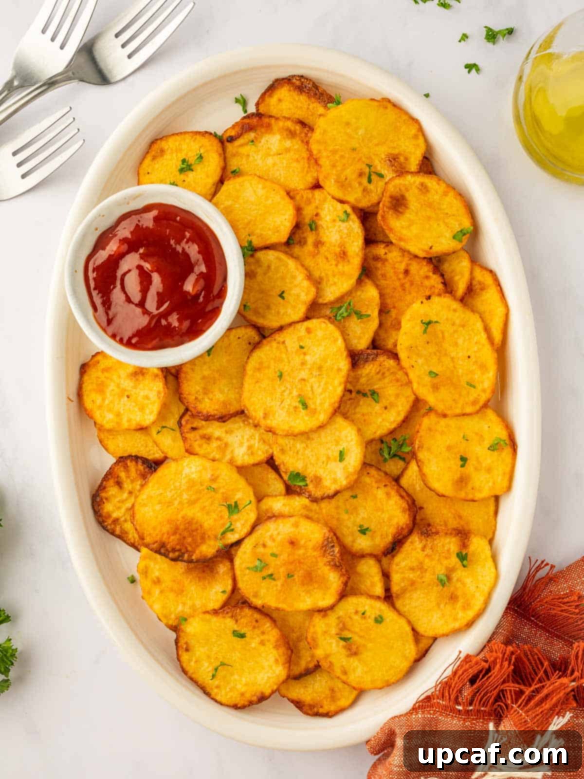 Golden Air-Fried Potato Coins 2 A large platter of crispy air fryer potato chips, with a small dish of ketchup on the side.