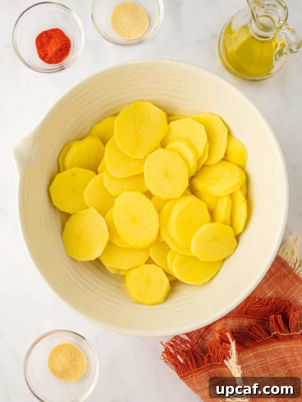 Golden Air-Fried Potato Coins 4 Thin slices of raw potato neatly arranged in a bowl, ready for seasoning.