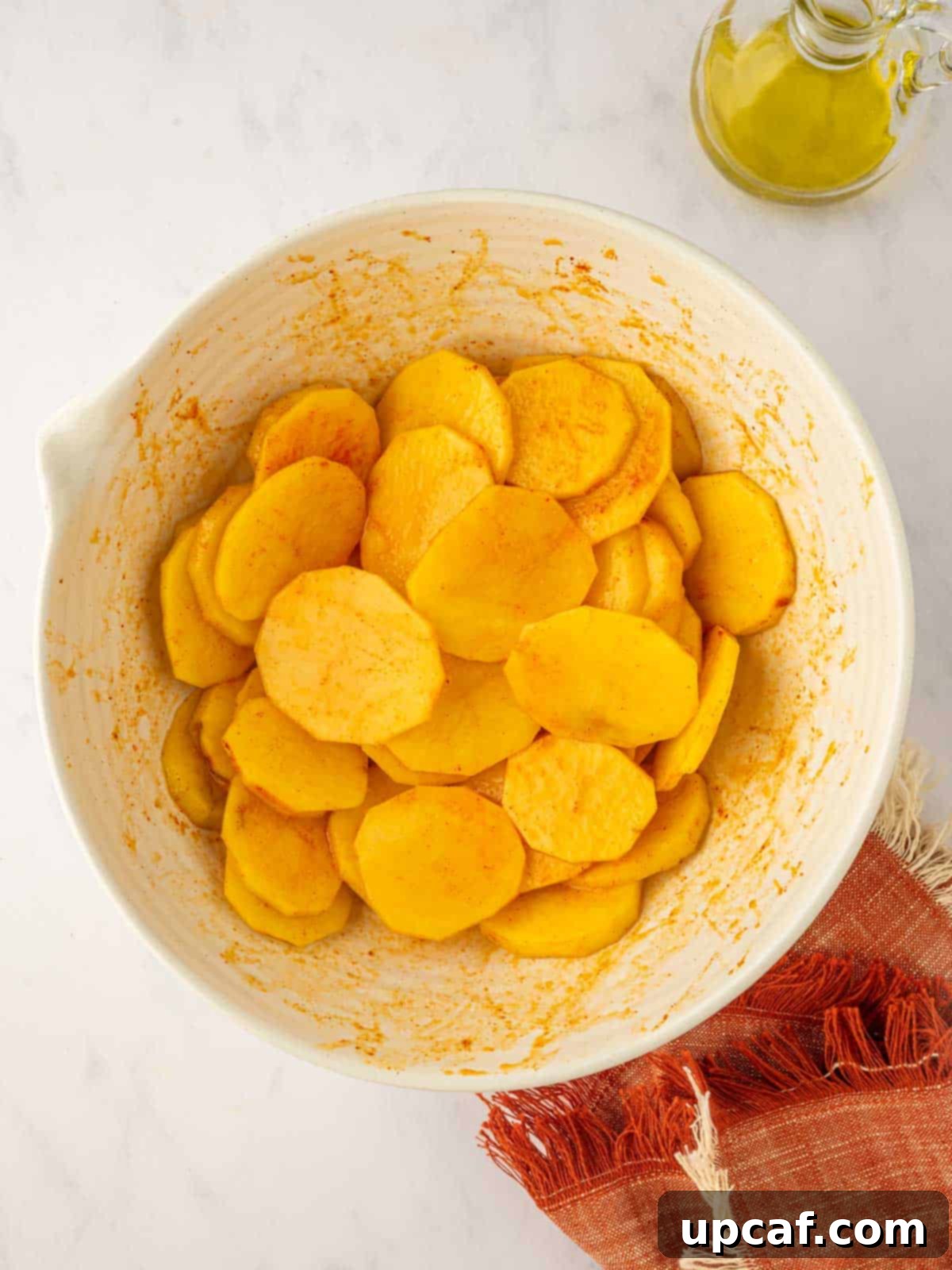 Golden Air-Fried Potato Coins 6 Sliced potatoes being tossed with seasoning in a bowl, showing an even coating.