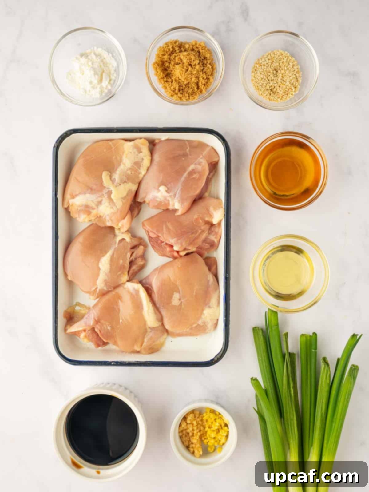Sweet and Sticky Panda Express Teriyaki Chicken 3 Ingredients for homemade Panda Express Teriyaki Chicken laid out on a cutting board including chicken thighs, soy sauce, ginger, garlic, and rice vinegar.