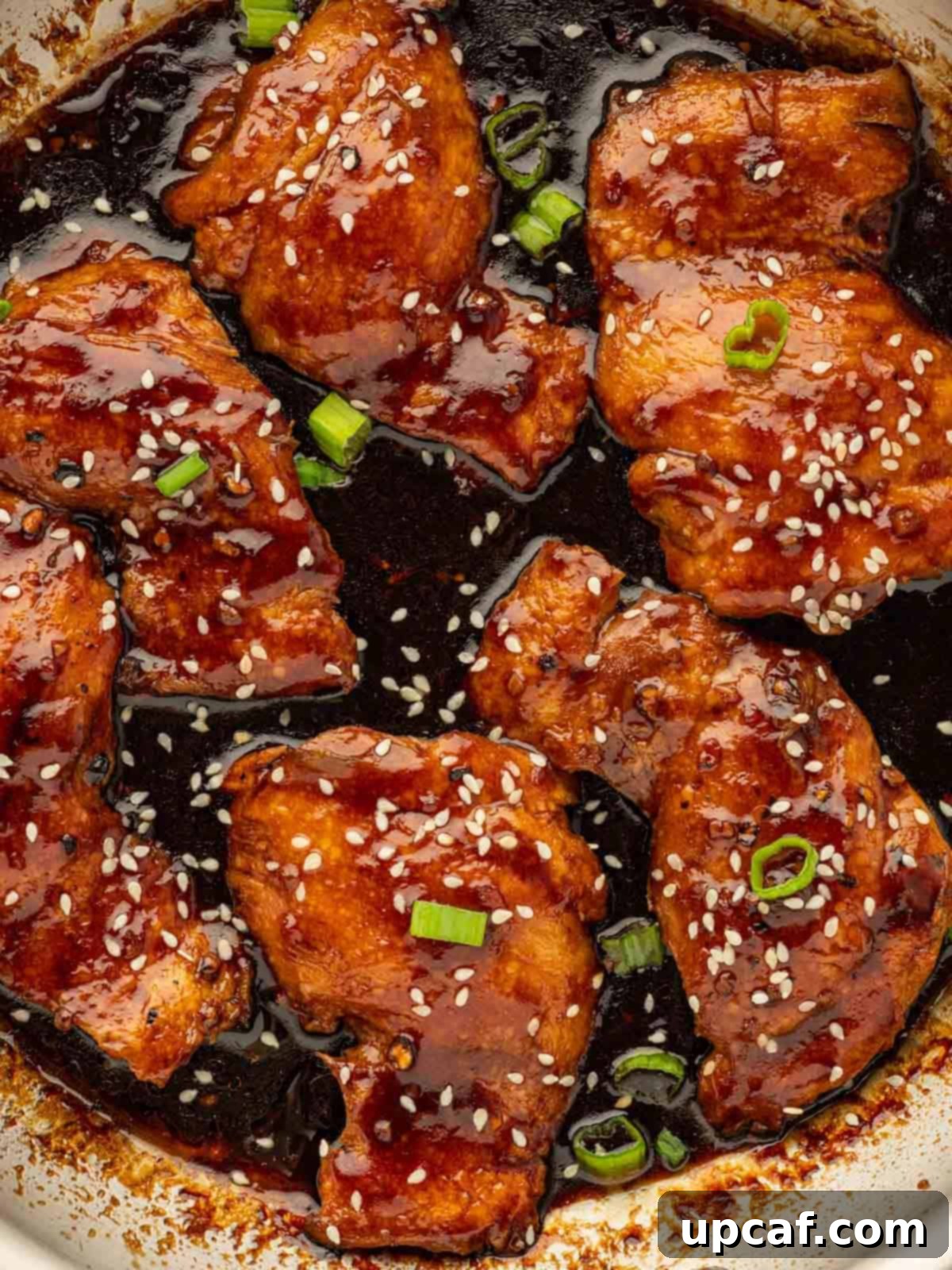 Sweet and Sticky Panda Express Teriyaki Chicken 10 Close-up shot of a skillet filled with rich, glossy Panda Express Teriyaki Chicken, garnished with green onions.